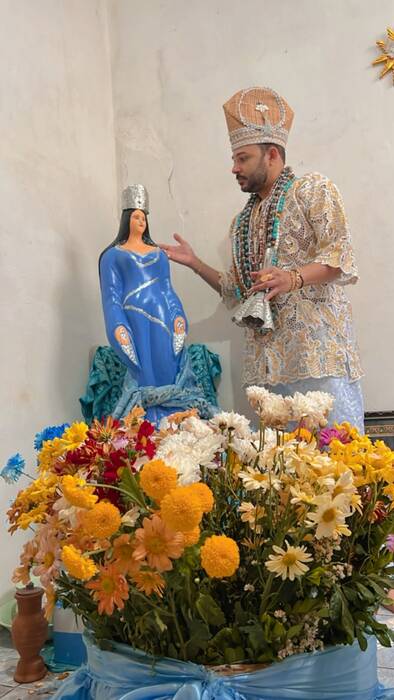Pai Léo de Oxalá junto à imagem de Iemanjá, com flores